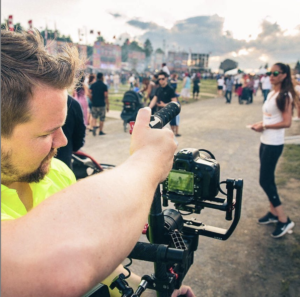 man holding a camera on gimbal filming a lively event
